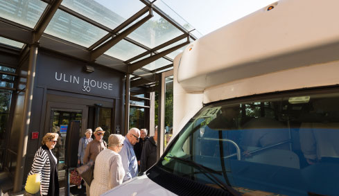 Six people outside a building waiting to enter a bus