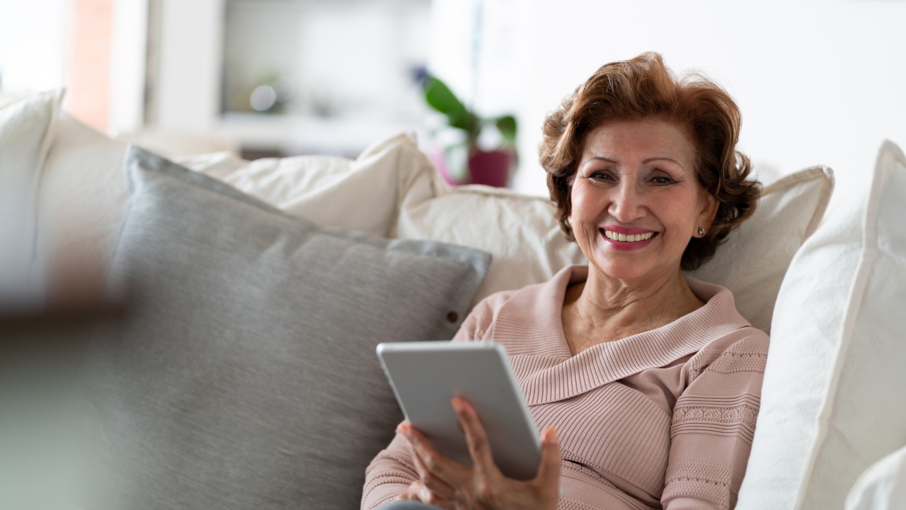 A woman smiling and holding a tablet