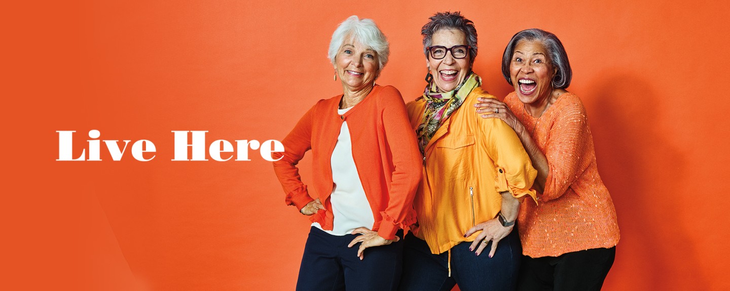 Live Here banner with three women standing in front of an orange background