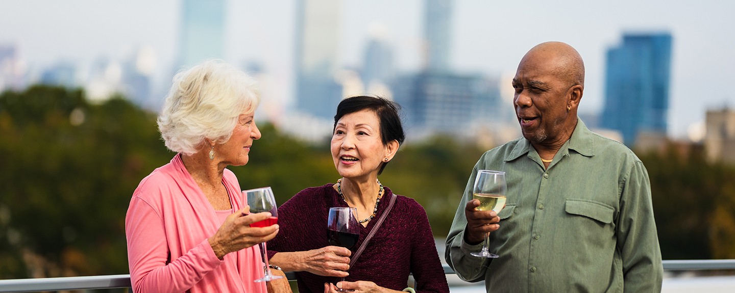 Three people on a rooftop holding glasses of wine
