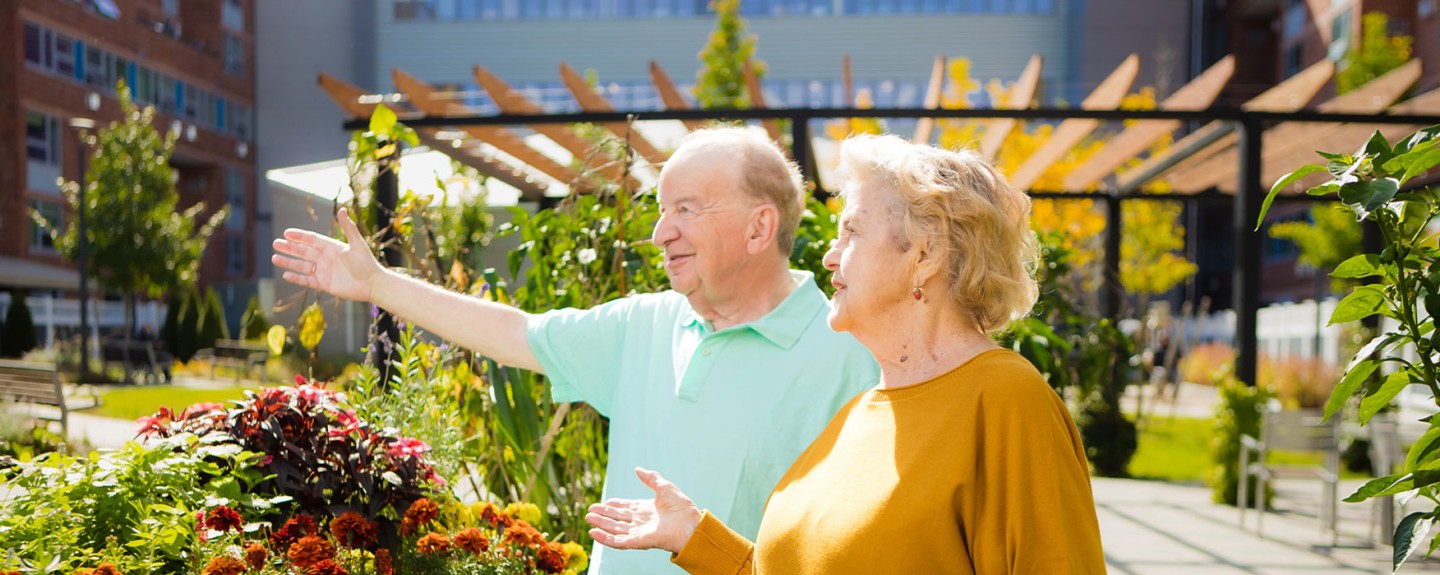 Two people standing outside as one shows off a garden