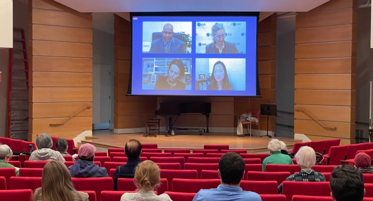 Walter Ramos, Amy Schectman, Annissa Essaibi-George, and Michelle Wu on screen in 2Life's Brighton Campus auditorium during the live broadcast of Candidate Forum: A Vision for Boston Seniors