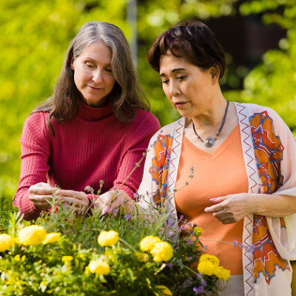 Two women tending to flowers in a garden.