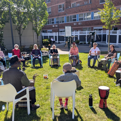 A group of seniors participating in an outdoor drum circle.