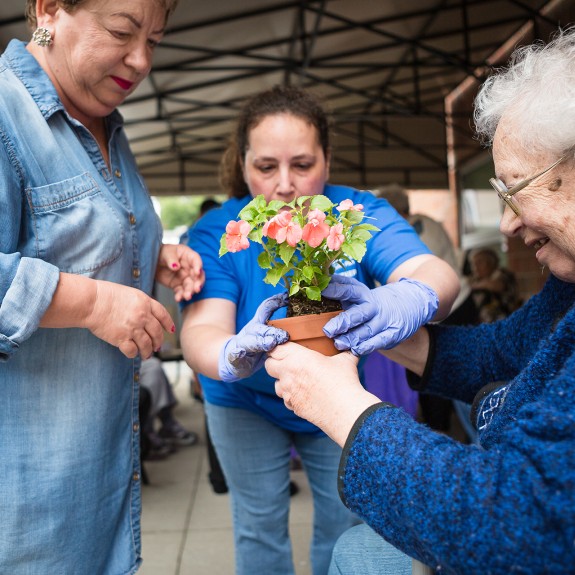 3 people around a pot of flowers