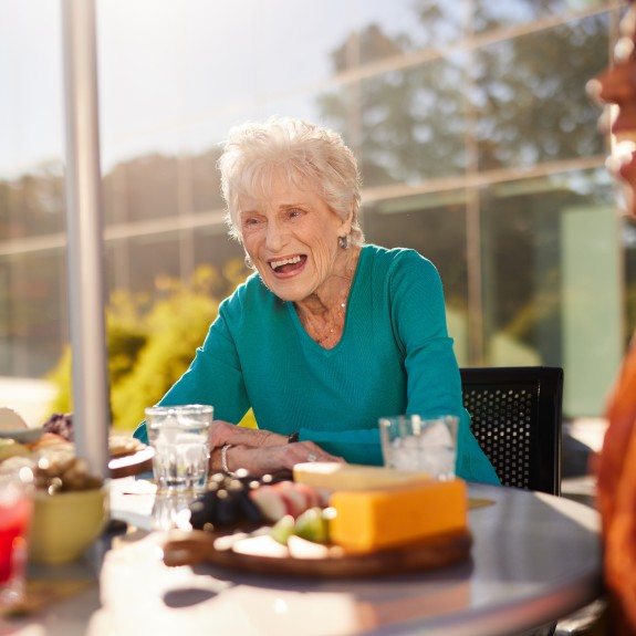 A woman in a green shirt sitting at an outdoors table having a meal with friends