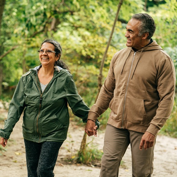 Two people holding hands walking through a forest