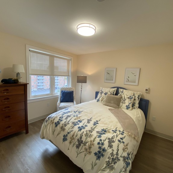 A bedroom with a full size bed, dresser and window