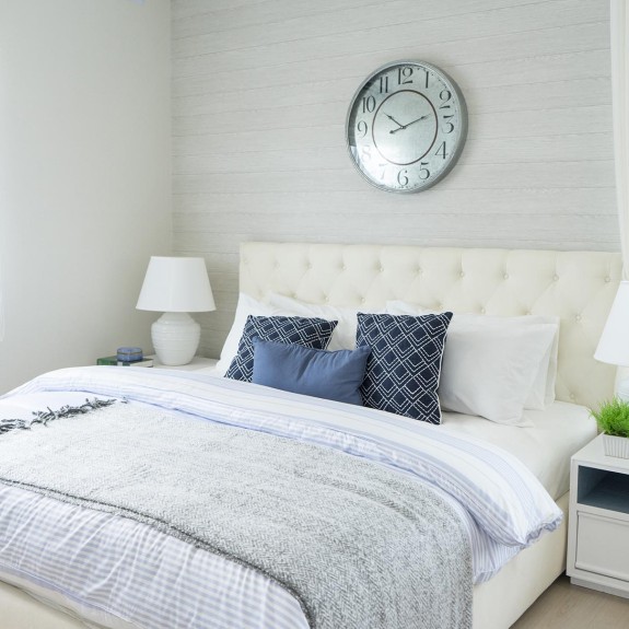 A bedroom with a full size bed, dresser and clock