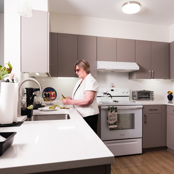 Someone cuts fruit on the counter of a clean and spacious kitchen