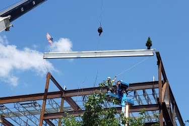 A crane lowering steel onto a building frame