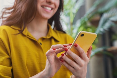 A woman scrolling on a yellow cell phone