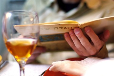 A glass of wine in front of a person reading a menu