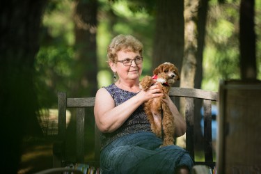 A woman sitting on a bench holding a small brown dog