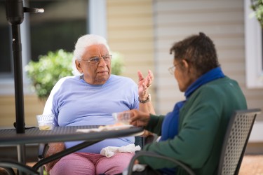 Two people talking at an outdoor table