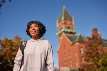 A woman standing outside with a red brick building in the background