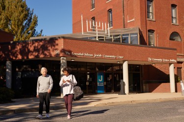 Two people walking in front of the Jewish Community Center