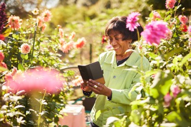 A woman smiling at a foldable phone in a field of flowers