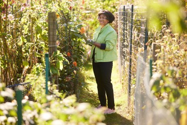 A woman standing in a garden checking the plants