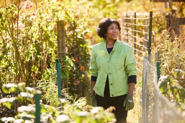A woman standing in a garden looking over a fence