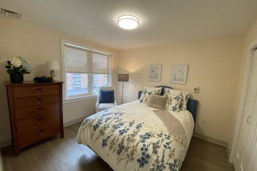 A bedroom with a full size bed, dresser and window