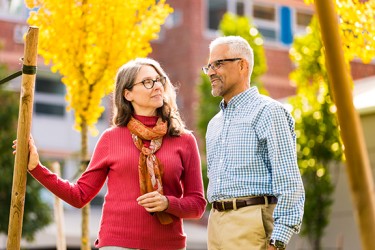 A woman in a red sweater looks up at a man in a blue plaid shirt and khakis