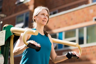 A light toned woman wearing a blue tank top exercises outside