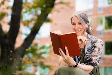 A woman in a green dress enjoys reading a book outside
