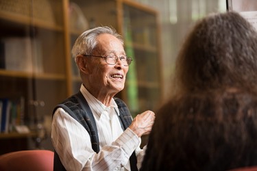 An Asian man sitting inside a library