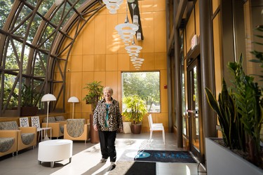 A person standing inside an atrium furnished with chairs and round tables