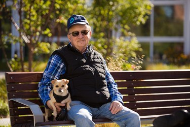 A man sitting on a bench with a small dog