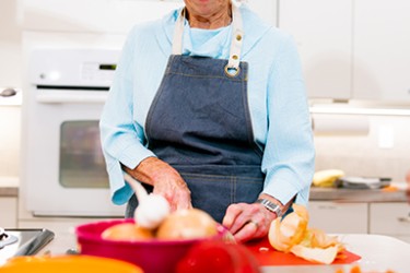 A woman wearing a blue apron and blue shirt working in a kitchen