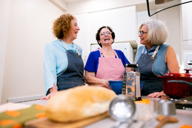 Three people standing in a kitchen and laughing together